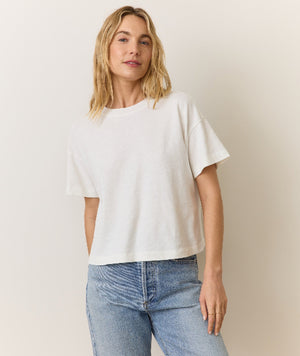 Woman wearing a white oversized t-shirt and light blue jeans against a plain background