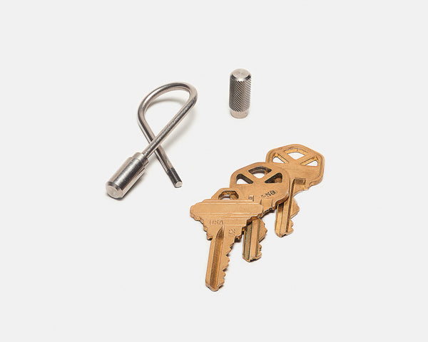 Set of brass keys and a keychain tool on a white background