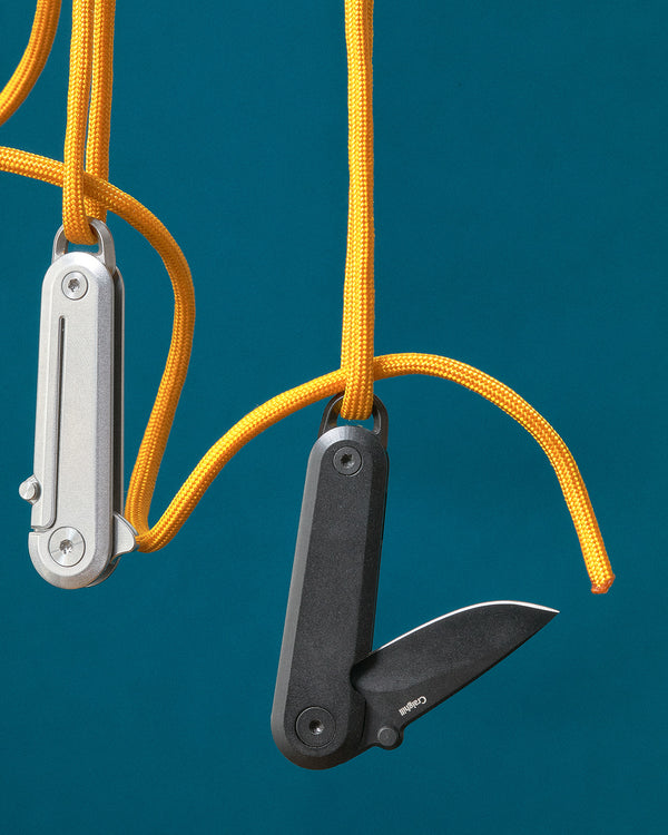 Two pocket knives on yellow strings against a blue background
