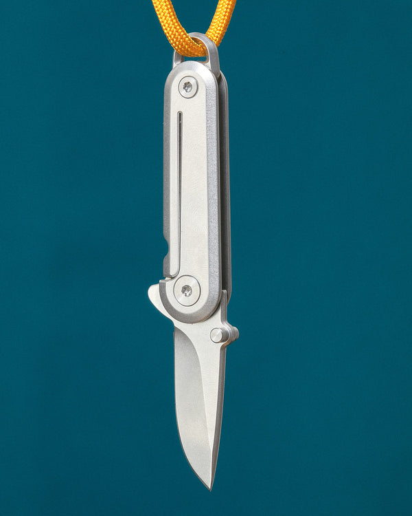 Folding knife with a yellow cord on a teal background
