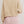Person wearing a beige textured sweater and pink shorts on a plain background