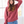 Person wearing a red hoodie and blue jeans indoors with a window in the background