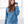 Woman wearing a blue hoodie in a bright room with large windows