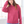 Woman wearing a pink hoodie in a bright room with large windows.