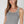 Woman wearing a sleeveless knitted top in cool grey on a plain background
