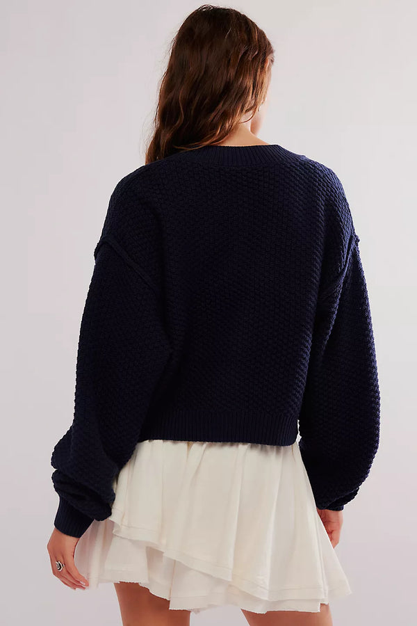 Person wearing a navy sweater and white skirt on a plain background