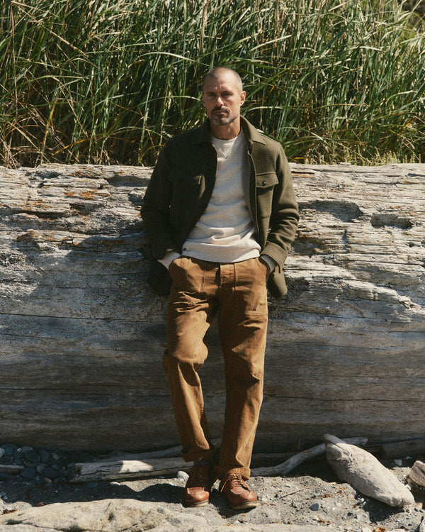 fit model leaning against the wall wearing The Maritime Shirt Jacket in Heather Olive Wool