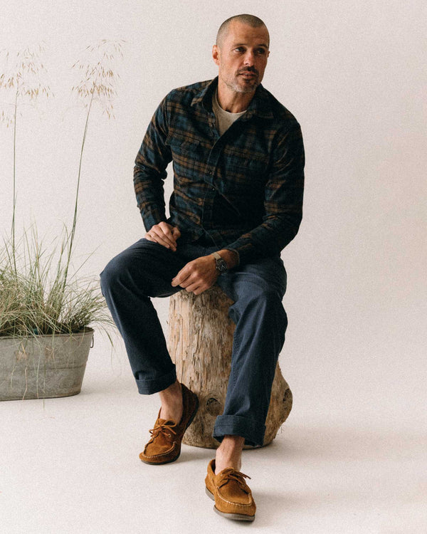 Man sitting on a log with a neutral background